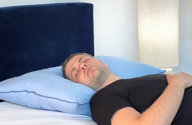 Uomo che dorme supino con la nuca appoggiata al Cuscino Chiropratico celeste